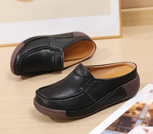 Vue détaillée de mules à plateforme en cuir noir pour femmes avec semelles compensées.