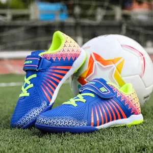 Blue children's turf soccer shoes with professional training cleats on grass field