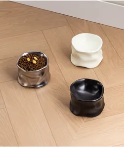 Primer plano de tres cuencos para mascotas de cerámica y metal con textura moldeada.