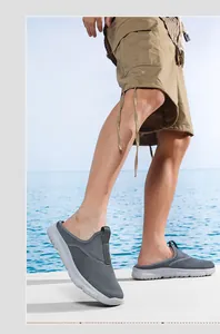 Dettaglio di sabot in mesh grigio traspirante indossati da un modello in riva al mare.