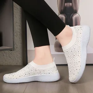 Breathable white fly-knit slip-on sneakers for women featuring sparkling rhinestone details