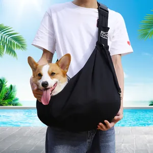 Adjustable black pet sling carrier for dogs and cats shown in outdoor use scenario