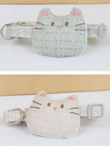 Close-up of cute cat-shaped plush pet collar accessories in soft green and beige finishes