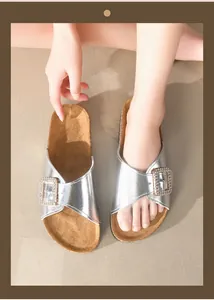 Detailopname van zilveren metallic slippers met fonkelende strass-gesp detail.