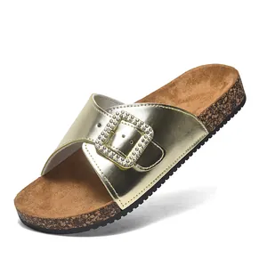 Modieuze gouden dames slippers met kristallen gesp en kurkzool voor de zomer 2025.