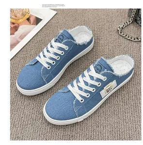 Zapatillas mule de lona vaquera azul con bordes deshilachados y suelas de goma blancas