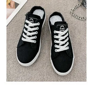 Vista superior de zapatillas tipo mule de lona negra con bordes deshilachados y cordones blancos