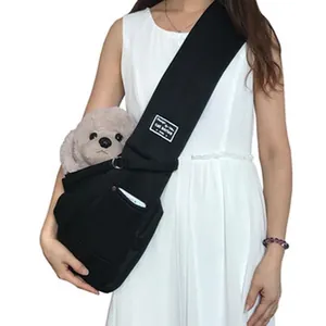 Black pet sling carrier bag demonstrated by a model with a toy dog for travel.