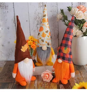 Drei Erntedankfest-Gnome mit Kürbishüten und weißen Bärten auf einem hölzernen Grund.