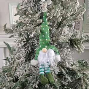 Niedlicher grüner gestrickter Weihnachtszwerg-Anhänger an einem verschneiten Zweig