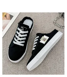 Vista detallada de mules de lona negra para mujer con cordones blancos y bordes deshilachados