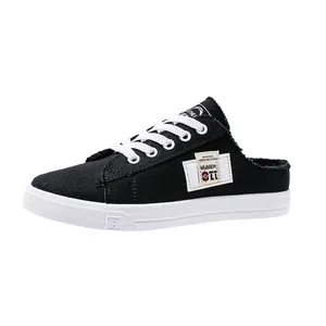 Vista detallada de zapatillas mule de lona negra para mujer con cordones blancos y parche.