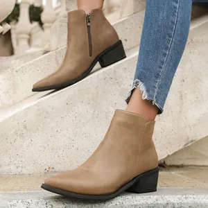 Detailed view of taupe pointed-toe booties with chunky heels on stone steps