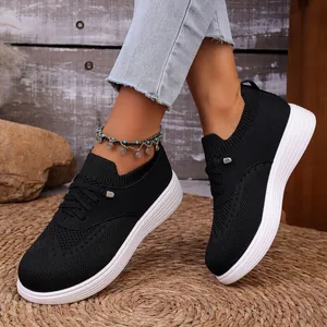 Detailopname van zwarte ademende slip-on sneakers voor dames met dikke witte zolen.