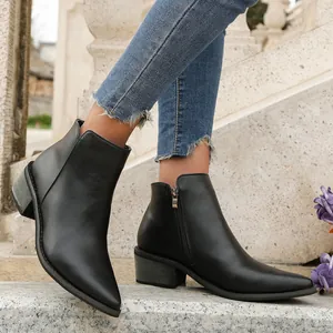 Elegant black pointed-toe ankle boots with side zipper and block heel on stone steps.