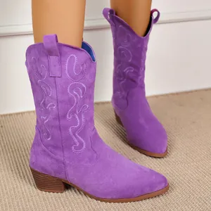 Detail view of purple suede cowboy boots with elegant embroidery and chunky heels