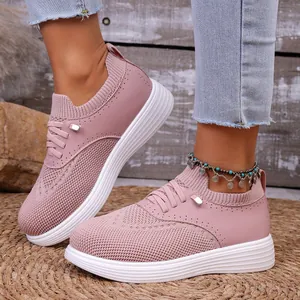 Close-up van roze ademende fly-knit slip-on sneakers met een dikke witte comfortabele zool.
