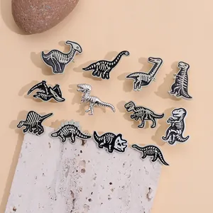 Collection of black and white punk skeleton dinosaur enamel pins on a natural stone base.