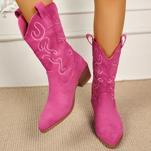 Close-up detail of bright pink embroidered western boots with pointed toe and chunky heel