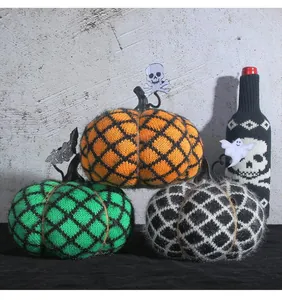 Handmade knitted pumpkins for Halloween party decoration in orange, green, and black.