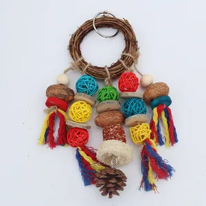 Close-up of a parrot chew toy with a rattan ring, colorful balls, and a natural pine cone.