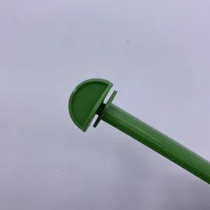 Dettaglio di un posatoio in plastica verde per gabbie di uccelli con attacco a semicerchio