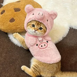 Close-up of a cat wearing a cute pink fuzzy pig-themed hood and matching plush vest