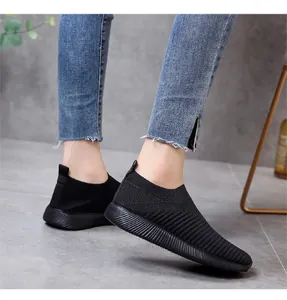 Κοντινό πλάνο μαύρα αναπνεύσιμα fly-knit αθλητικά παπούτσια slip-on με τζιν παντελόνι.