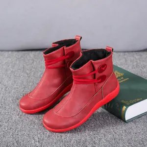 Close-up of red British style leather ankle boots with button and strap details