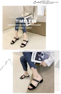 Primer plano de sandalias negras minimalistas con un tacón de bloque bajo y tiras dobles.