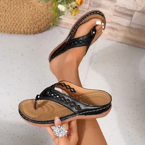 Detailansicht schwarzer Keil-Flip-Flops mit Ausschnitten und weicher brauner Sohle