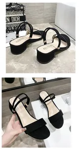 Detalle de sandalias negras de tacón bajo con correas versátiles y hebilla dorada