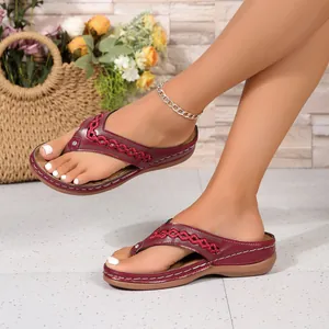 Nahaufnahme von weinroten Keil-Flip-Flops mit geflochtenen Riemen und Ziernähten