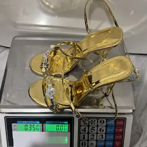 Detailansicht der Gewichtsmessung für goldene Stöckelsandalen mit Metallblumen
