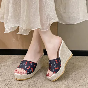 Détail de sandales compensées à imprimé cerises avec talon en lin texturé et bout ouvert.