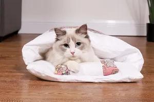 Primo piano di un gatto soffice in un sacco a pelo per animali bianco semichiuso
