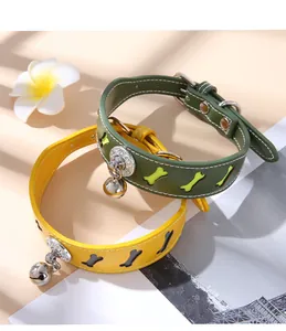 Close-up of green and yellow pet collars with bone-shaped cutouts and silver bells.