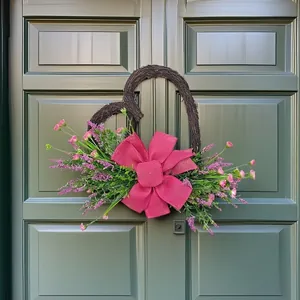 Handgefertigter, herzförmiger Türkranz mit rosa Kunstblumen und magentafarbener Schleife