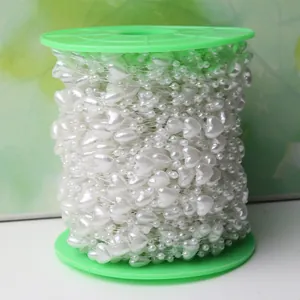 Détail de perles nacrées blanches en forme de cœur sur une bobine en plastique vert