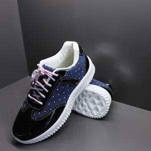 Detailopname van marineblauwe canvas schoenen met stippen, roze veters en een witte zool.