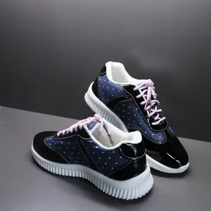 Gedetailleerde weergave van marineblauwe stippensneakers met roze veters en zolen