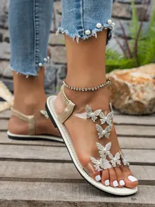 Elegantes sandalias planas con mariposas de pedrería y tiras transparentes para verano.