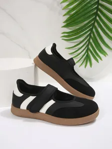 Detalle de zapatos Mary Jane negros con rayas blancas y suela de goma resistente.
