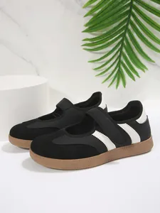 Vista lateral de zapatillas Mary Jane retro negras con rayas y tira de velcro