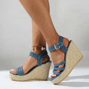 Detail view of denim wedge sandals with braided straw platform and ankle strap