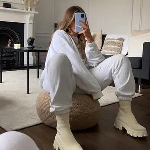 Beige platform soklaarzen gestyled met witte loungewear in een moderne thuisomgeving.
