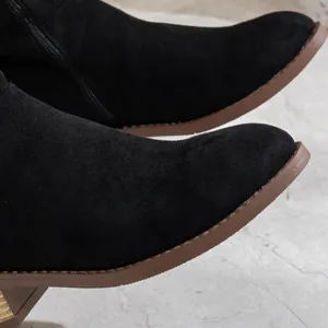 Detailansicht schwarzer Overknee-Stiefel aus Wildleder mit Reißverschluss und Blockabsatz.