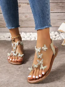 Vista detallada de sandalias planas para mujer con adornos de mariposas de pedrería.