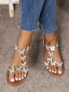 Vista detallada de los adornos de mariposa con diamantes de imitación en sandalias