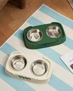 Stainless steel double pet feeding bowls in green and cream-white colors on striped rug